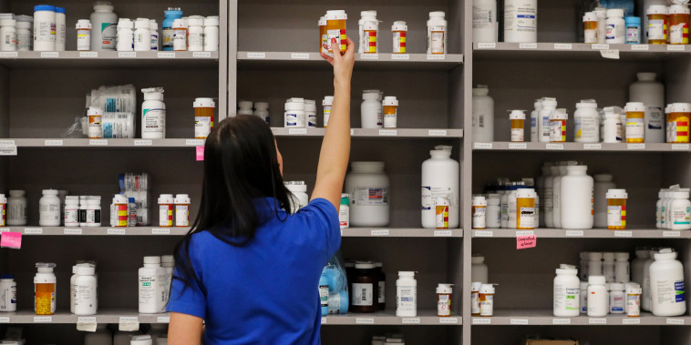 A pharmacy technician grabs a bottle of drugs off a shelf in Midvale, Utah, on Sept. 10, 2018.