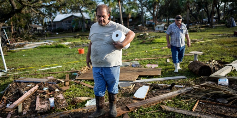 Image: Buddy Ellison, left, and his father Dan look through debris scattered across their property in Horseshoe Beach, Fla., on Aug. 31, 2023, one day after the passage of Hurricane Idalia. 