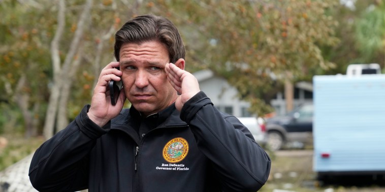 Florida Gov. Ron DeSantis talks on the phone with President Joe Biden as he stands outside storm-damaged restaurant Shrimp Boat during a visit to Horseshoe Beach, Fla., one day after the passage of Hurricane Idalia, on Aug. 31, 2023. 