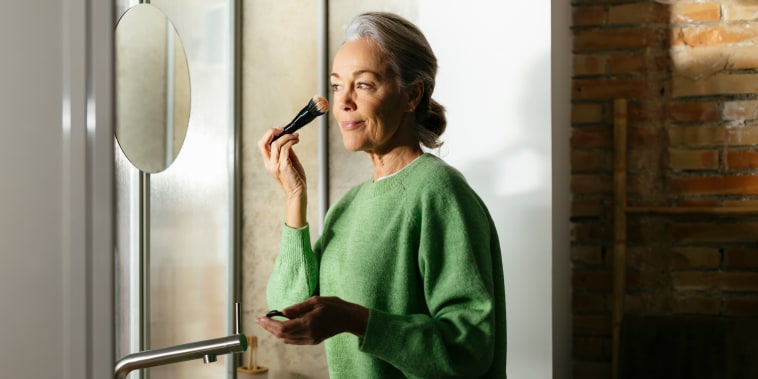 Woman doing make-up with brush at home