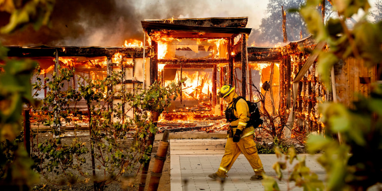 Woodbridge firefighter Joe Zurilgen passes a burning home as the Kincade Fire rages in Healdsburg, Calif., 