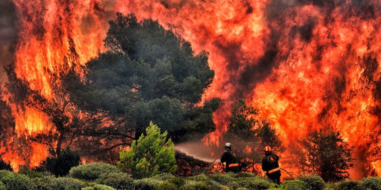 Firefighters try to extinguish flames during a wildfire at the village of Kineta, near Athens, on July 24, 2018. - Raging wildfires killed 74 people including small children in Greece, devouring homes and forests as terrified residents fled to the sea to escape the flames, authorities said Tuesday. 