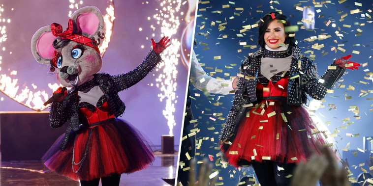 On the left, a person in a mouse costume and red dress sings onstage. On the right, Demi Lovato in the same red dress smiles and waves amid gold confetti.