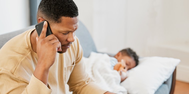 Worried father concerned, caring for sick son calling a doctor and taking temperature check of his sleeping kid at home. Parent consulting with professional and taking care of child with fever
