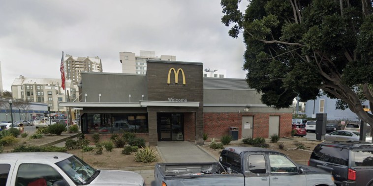 A new-looking mcDonalds with a drive-thru and cars parked out front.