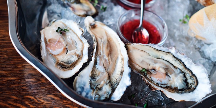 Oysters are on a plate with ice and sauce