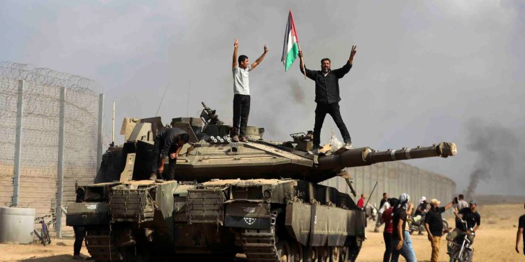 Image: Palestinians celebrate atop a destroyed Israeli tank east of Khan Younis at the Gaza Strip.