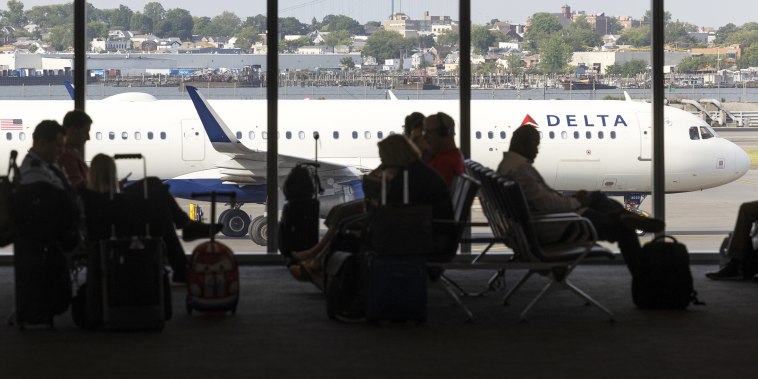 Passengers at a Delta gate with an airplane outside at LaGuardia Airport 