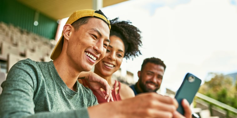 People outdoors smiling at phone.