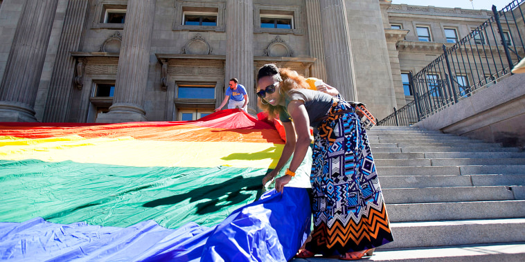 People unroll a large rainbow flag at the Idaho state Capitol