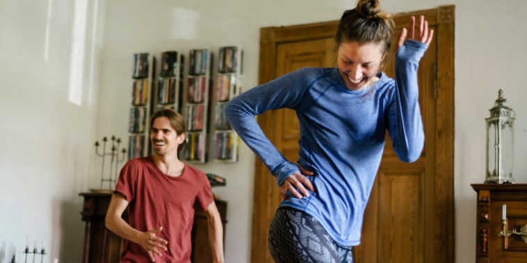 A young couple working out doing some aerobic exercises at home together.