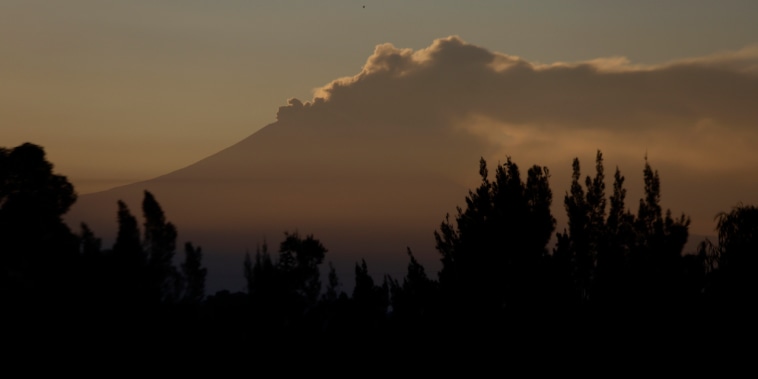 Vista del Volcán Popocatépetl desde la Ciudad de México emitiendo humo al amanecer.