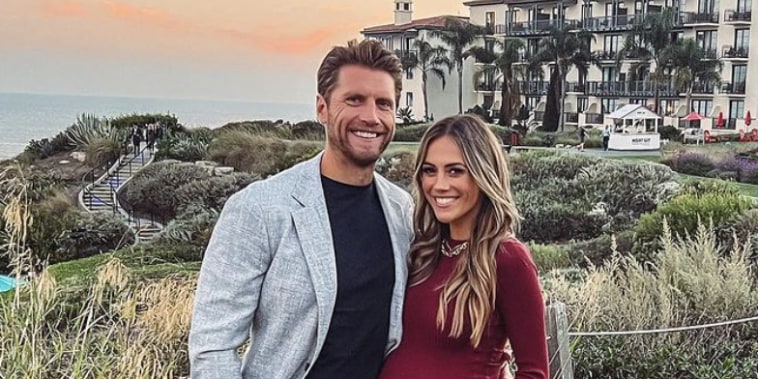 Jana Kramer and Allan Russell stand in front of a seaside resort