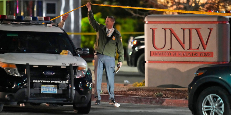 A police officer walks under crime scene tape in the aftermath of a shooting at the University of Nevada, Las Vegas, on Dec. 6, 2023.
