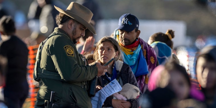 Un oficial de la Patrulla Fronteriza habla con migrantes en Eagle Pass, Texas. 
