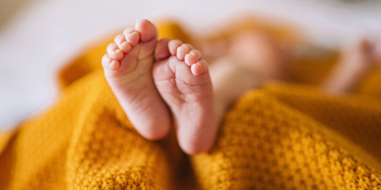 Tiny newborn baby feet in a yellow blanket