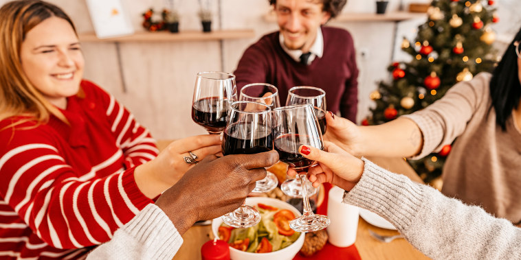 Group of young friends toasting wine while having christmas lunch at home.