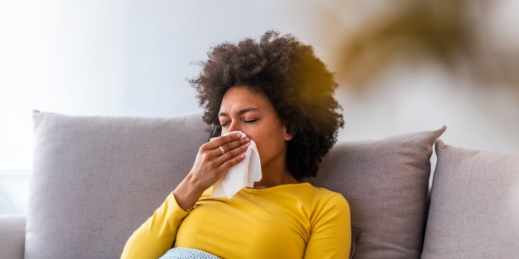 Woman sneezing in a tissue in the living room.
