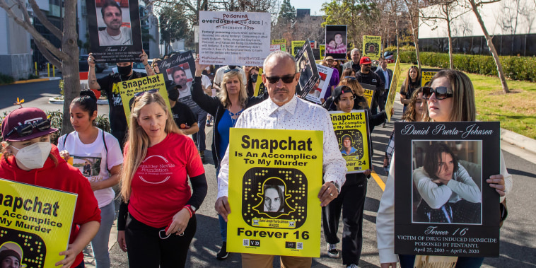 People march in front of Snap, Inc.'s headquarters holding signs to protest.