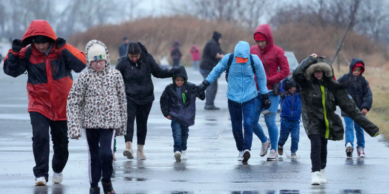 Migrantes caminan bajo la lluvia en el Floyd Bennett Field, en Brooklyn, Nueva York, el martes 9 de enero de 2024.