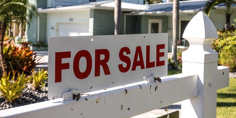 A 'For Sale' sign in front of a single family home