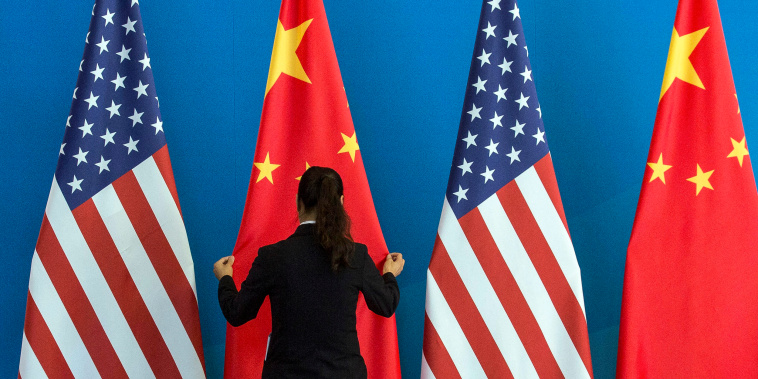 A woman adjusts a flag during the U.S.-China Strategic and Economic Dialogue in Beijing