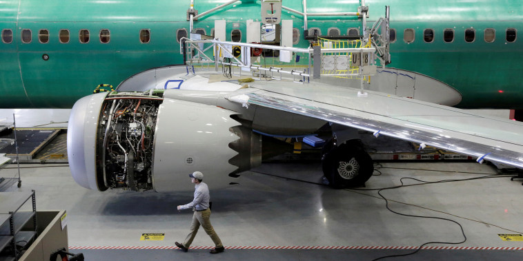 A worker walks past a Boeing 737 MAX-9 under construction at their production facility in Renton, Wash.