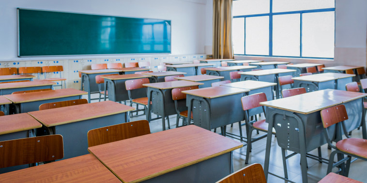 Empty classroom with desks, chairs and chalkboard.