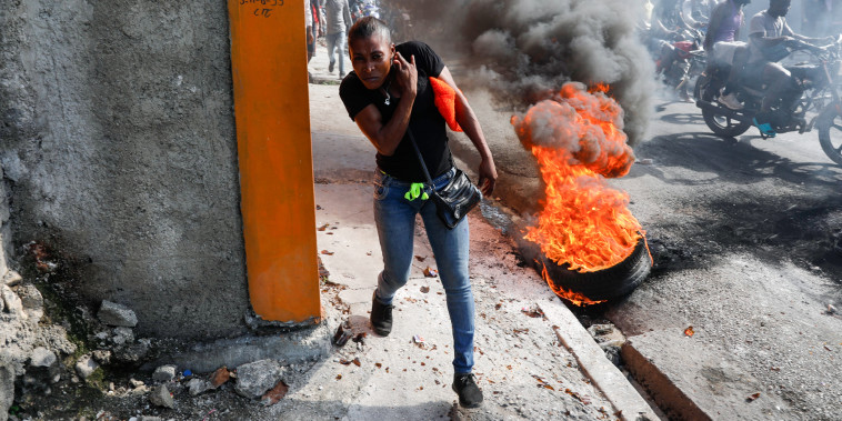 A person runs past burning tires in Haiti