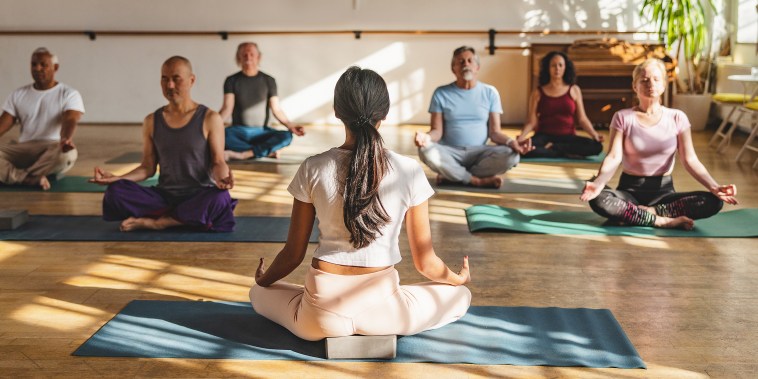 Group of multicultural yoga participants seated and meditating.
