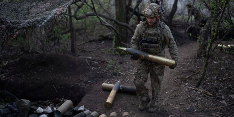 A Ukrainian serviceman from Azov brigade carries a shell for the OTO Melara Mod 56 howitzer on the frontline near Kreminna in the Donetsk region, Thursday, April 11, 2024.