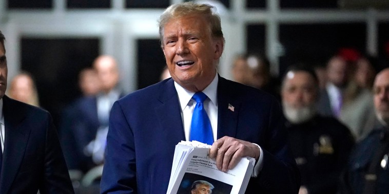 Former President Donald Trump holds news clippings as he leaves court for the day on April 18, 2024.