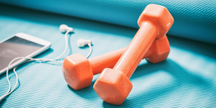 Dumbbells and a smartphone on a blue yoga mat