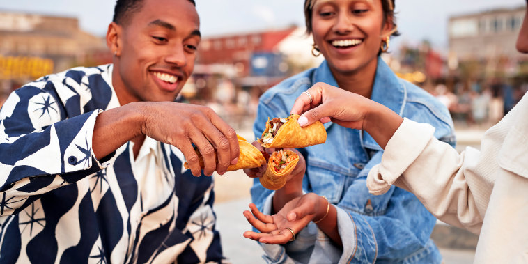 Multiracial friends toasting tacos on promenade