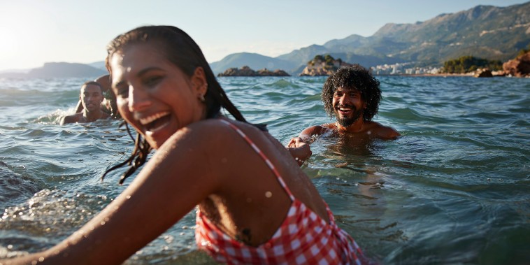 Happy young woman holding hand of boyfriend while enjoying swim in sea on sunny day