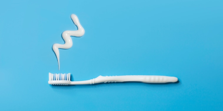 Flat lay white toothbrush and tooth paste on blue background.