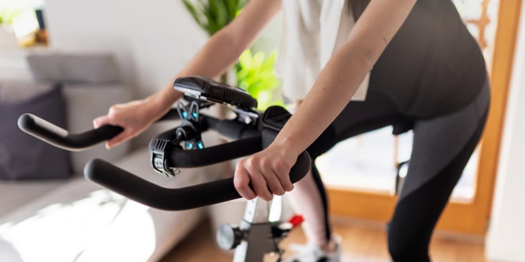 Low section of woman training on exercise bike at home.