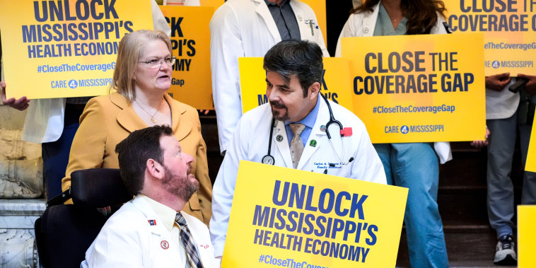Doctors hold signs saying "Unlock Mississippi's Health Economy" at the Mississippi State Capitol