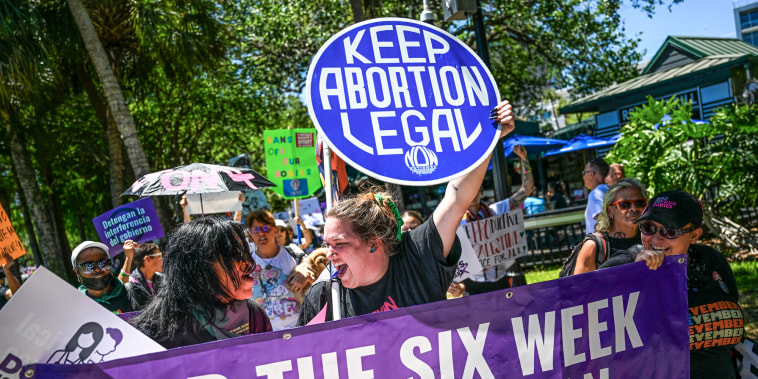 Pro abortion rights protestors hold signs saying "Keep Abortion Legal" and "End the Six Week Abortion Ban"