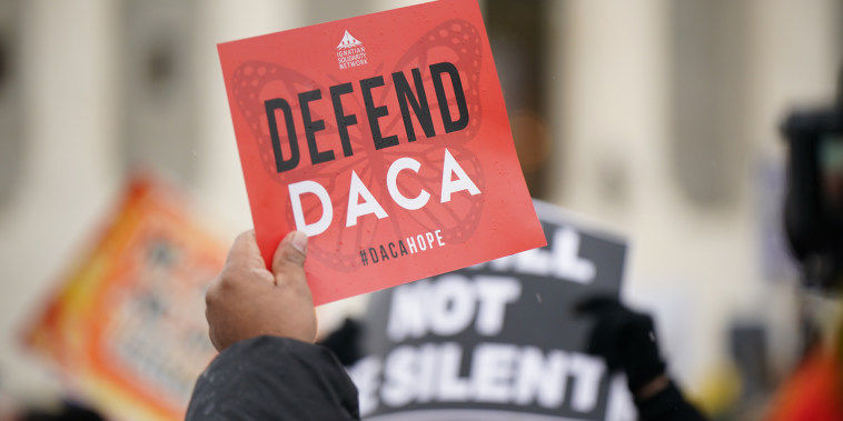 An activist holds a "Defend Daca" sign in front of the Supreme Court