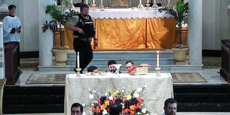 A police officer walks through St. Mary Magdalen in Abbeville, La., after a teenager armed with a rifle tried to enter the church Saturday, May 11, 2024, in an image from the church's livestream. 