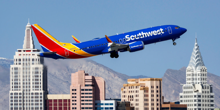 A Boeing 737 MAX 8 Southwest airplane flies above buildings