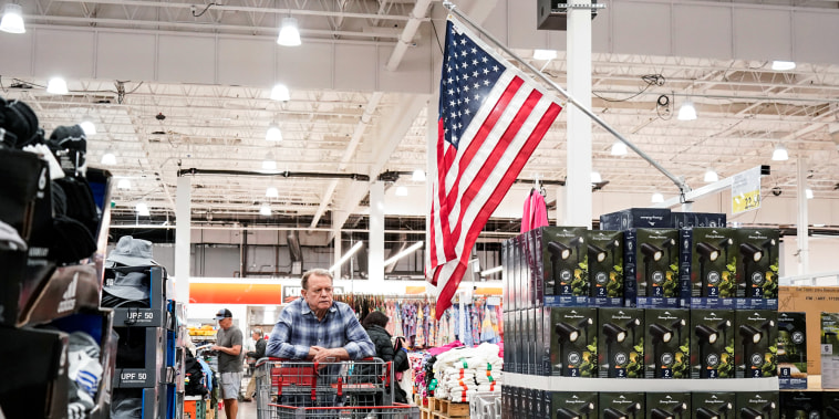 Customers select goods at a supermarket with the American flag hanging overhead