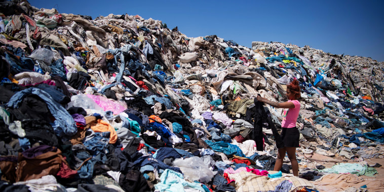 A woman digs through tons of discarded clothes in the Atacama desert in Chile on September 26, 2021.