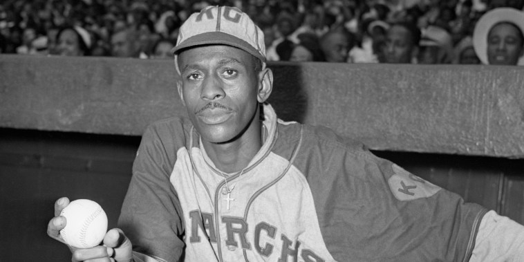 Pitcher Satchel Paige stands at the top of the dugout with baseball in hand