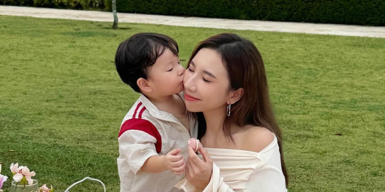Jasmine Yongs son kisses her on the cheek on a picnic blanket outside 
