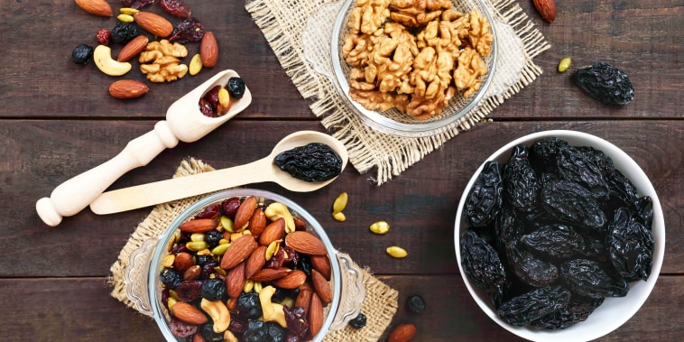 Many different nuts, dried berries, prunes, pumpkin seeds in bowls.