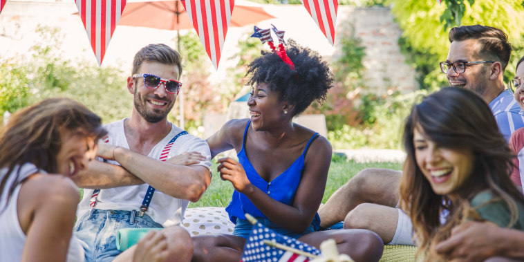 friends in backyard on picnic blanket with American flags.