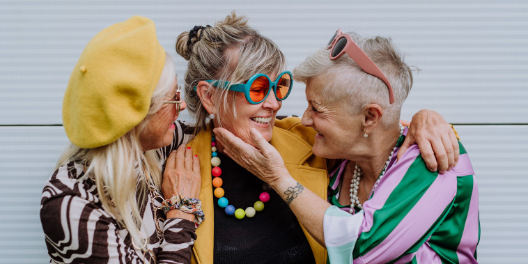 Portrait of happy three senior friends in colourful clothes.