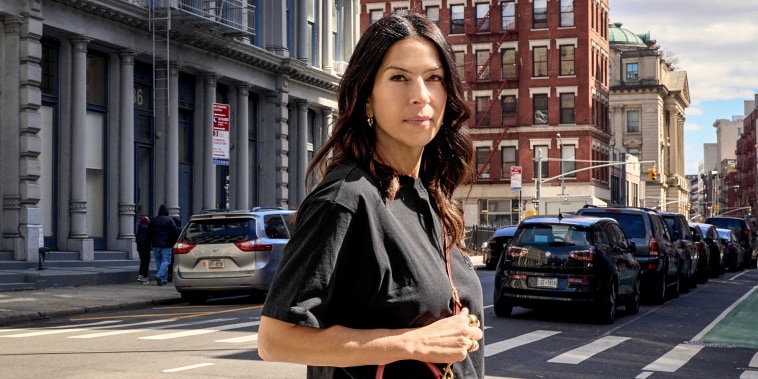 Rebecca Minkoff stands on the crosswalk of a street in the city on a sunny day